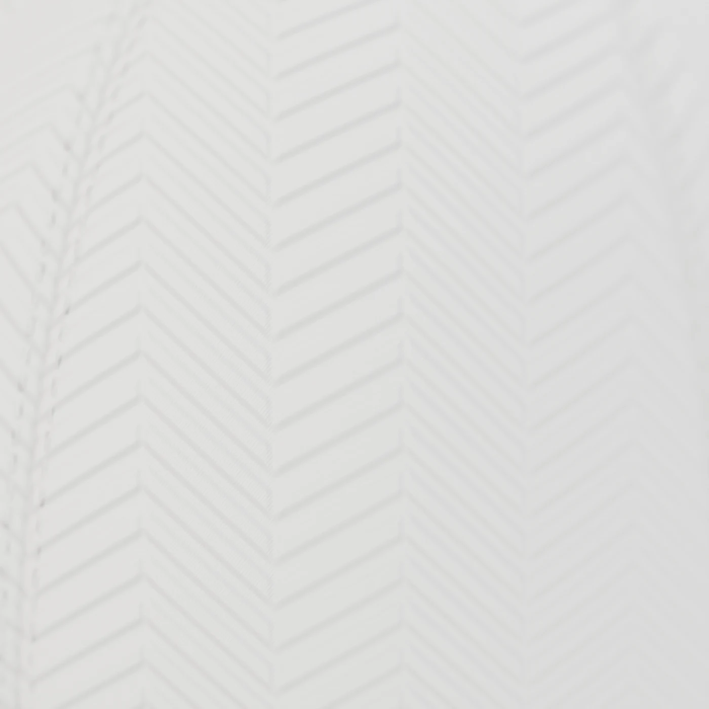 Macro of the white-on-white herringbone motif and a stitched panel seam